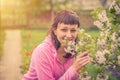 Young beautiful female woman looking at camera, smiling and smelling flowers of cherry tree blossom Royalty Free Stock Photo