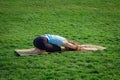 Young beautiful fit woman doeing yoga asans on the green grass with yoga mat Royalty Free Stock Photo