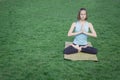 Young beautiful fit woman doeing yoga asans on the green grass with yoga mat Royalty Free Stock Photo