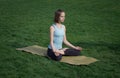 Young beautiful fit woman doeing yoga asans on the green grass with yoga mat Royalty Free Stock Photo