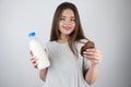 Young beautiful fit woman holding bottle with milk in one hand and chocolate cookies in another looking hungry healthy lifestyle Royalty Free Stock Photo