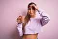 Young beautiful fitness woman drinking protein chocolate milkshake before gym stressed with hand on head, shocked with shame and