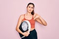 Young beautiful fitness woman wearing sport clothes holding weighting machine scale with angry face, negative sign showing dislike Royalty Free Stock Photo