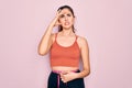 Young beautiful fitness woman wearing sport excersie clothes using measuring tape stressed with hand on head, shocked with shame Royalty Free Stock Photo