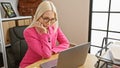 Young, beautiful, and focused, blonde businesswoman hard at work on her laptop in a relaxed office environment