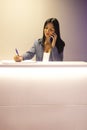 Young beautiful focused receptionist speaks on phone and writes down notes about client Royalty Free Stock Photo