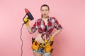 Young beautiful fun handyman woman in plaid shirt, denim shorts, kit tools belt full of variety instruments holding Royalty Free Stock Photo