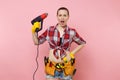 Young beautiful fun handyman woman in plaid shirt, denim shorts, kit tools belt full of variety instruments holding Royalty Free Stock Photo