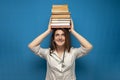 Young beautiful funny girl the nurse holds many books on a blue background and is smiling, the student is studying in a medical Royalty Free Stock Photo