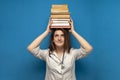 Young beautiful funny girl the nurse holds many books on a blue background and is surprised, the student is studying in a medical Royalty Free Stock Photo