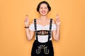 Young beautiful german woman with blue eyes wearing traditional octoberfest dress gesturing finger crossed smiling with hope and Royalty Free Stock Photo