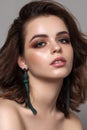 Young beautiful girl with amazing eyes, professional makeup, trendy colorful eyeshadows and fashion long green earrings. Royalty Free Stock Photo