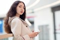 Young beautiful girl Asian, uses mobile phone, background, shopping Mall or business center