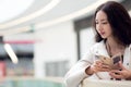 Young beautiful girl Asian, uses mobile phone, background, shopping Mall or business center