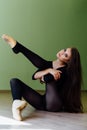 Young beautiful girl ballet dancer sits on the floor in the studio for dancing classes.