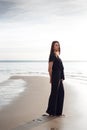 Young beautiful girl in black clothes walking on the beach. She walks along shore. A walk at sunset. Nobody around Royalty Free Stock Photo