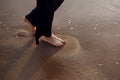 Young beautiful girl in black clothes walking on the beach. She walks along shore. A walk at sunset. Nobody around Royalty Free Stock Photo