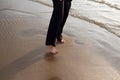 Young beautiful girl in black clothes walking on the beach. She walks along shore. A walk at sunset. Nobody around Royalty Free Stock Photo