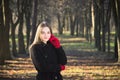 Young beautiful girl in a black coat red gloves exploring spring forest park.