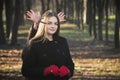 Young beautiful girl in a black coat red gloves exploring spring forest park.