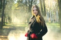 Young beautiful girl in a black coat red gloves exploring spring forest smoke park.