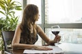 A young beautiful girl in a black dress sits in a restaurant and drinks wine from a glass. close up of young woman which Royalty Free Stock Photo