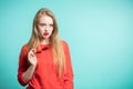 Young beautiful girl with blond hair on a blue background looking aside, holding and biting sunglasses Royalty Free Stock Photo