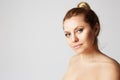 Young beautiful woman with blonde hair fixed behind, big eyes, thick eyebrows and naked shoulders smiling on gray Royalty Free Stock Photo