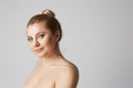 Young beautiful girl with blonde hair fixed behind, big eyes, thick eyebrows and naked shoulders smiling on gray Royalty Free Stock Photo