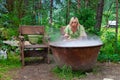 A young beautiful girl, a blonde witch is preparing a potion in a large cauldron on the eve of Halloween or the worshiping devil