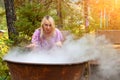 A young beautiful girl, a blonde witch is preparing a potion in a large cauldron on the eve of Halloween or the worshiping devil