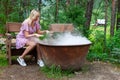 A young beautiful girl, a blonde witch is preparing a potion in a large cauldron on the eve of Halloween or the worshiping devil