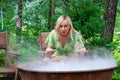 A young beautiful girl, a blonde witch is preparing a potion in a large cauldron on the eve of Halloween or the worshiping devil