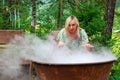 A young beautiful girl, a blonde witch is preparing a potion in a large cauldron on the eve of Halloween or the worshiping devil Royalty Free Stock Photo