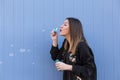 Young beautiful girl blowing bubbles outdoors over blue background Royalty Free Stock Photo