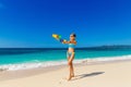 Young beautiful girl in blue bikini having fun on a tropical beach with toy water guns. Blue sea and sky in the background. Royalty Free Stock Photo