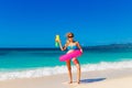 Young beautiful girl in blue bikini having fun on a tropical beach with toy water guns. Blue sea and sky in the background. Royalty Free Stock Photo