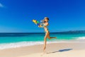 Young beautiful girl in blue bikini having fun on a tropical beach with toy water guns. Blue sea and sky in the background. Royalty Free Stock Photo