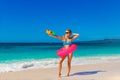 Young beautiful girl in blue bikini having fun on a tropical beach with toy water guns. Blue sea and sky in the background. Royalty Free Stock Photo