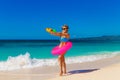 Young beautiful girl in blue bikini having fun on a tropical beach with toy water guns. Blue sea and sky in the background. Royalty Free Stock Photo