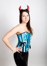 Young beautiful girl in blue corset with red horns looks like pretty Devil Royalty Free Stock Photo