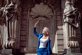 A young beautiful girl, in blue jacket, shielded from the sun in the city, against the background of historic buildings.