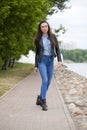 Young beautiful girl in blue jeans and a blue shirt on the background of spring street Royalty Free Stock Photo