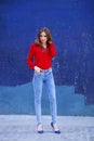 Young beautiful girl in blue jeans and a red shirt on the backgr Royalty Free Stock Photo