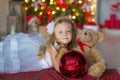 Young beautiful girl in blue white elegant evening dress sitting on floor near christmas tree and presents on a new year Royalty Free Stock Photo