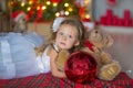 Young beautiful girl in blue white elegant evening dress sitting on floor near christmas tree and presents on a new year Royalty Free Stock Photo