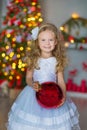 Young beautiful girl in blue white elegant evening dress sitting on floor near christmas tree and presents on a new year Royalty Free Stock Photo