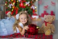 Young beautiful girl in blue white elegant evening dress sitting on floor near christmas tree and presents on a new year Royalty Free Stock Photo