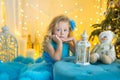 Young beautiful girl in blue white elegant evening dress sitting on floor near christmas tree and presents on a new year Royalty Free Stock Photo