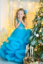 Young beautiful girl in blue white elegant evening dress sitting on floor near christmas tree and presents on a new year Royalty Free Stock Photo